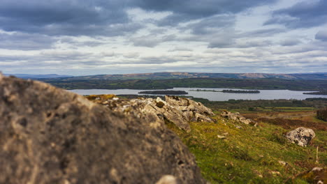 Timelapse-of-rural-nature-farmland-with-line-of-rocks-in-the-foreground-and-lake-and-hills-in-distance-during-sunny-cloudy-day-viewed-from-Carrowkeel-in-county-Sligo-in-Ireland