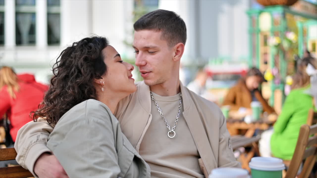A happy couple outdoors near a cafe. Hugging each other, kissing, smiling and talking, coffee. Autumn atmosphere