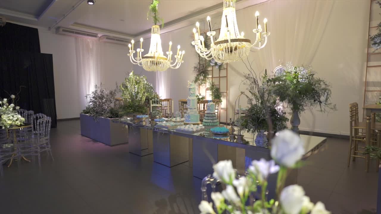 Wide shot of elegant event hall with chandeliers and mirrored dessert table