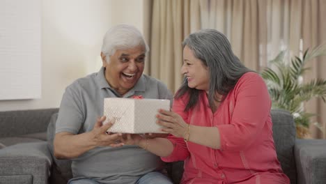 happy old indian wife surprises husband with a gift