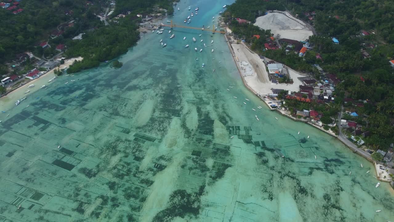 항공 4k 드론 영상: 발리의 누사 렘본간 섬과 누사 세닌간 섬을 연결하는 상징적이고 그림 같은 노란 다리를 가로지르는 스쿠터