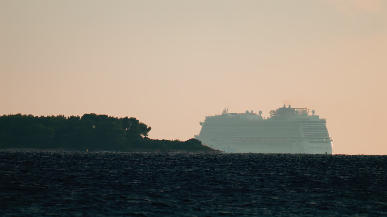 A large cruise ship sailing near the coast of Cannes, France, at sunset