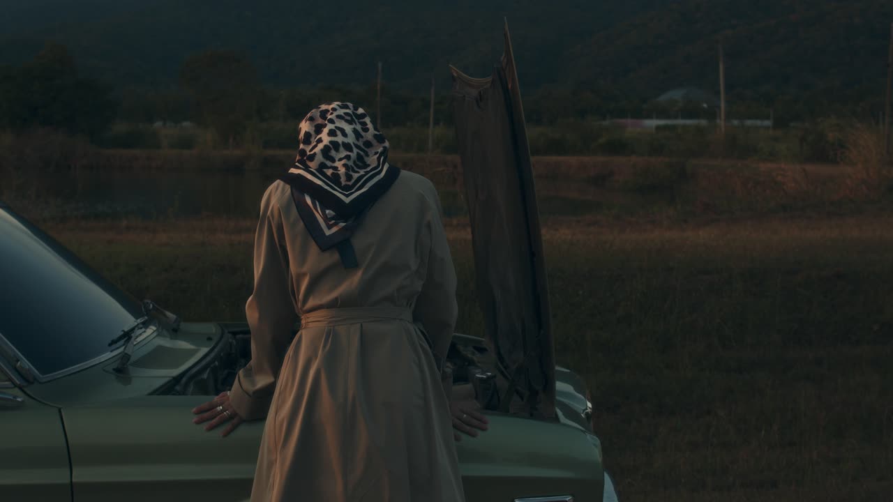 Woman Fixing a Vintage Car at Sunset