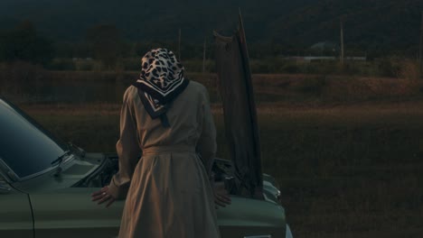 woman fixing a vintage car at sunset