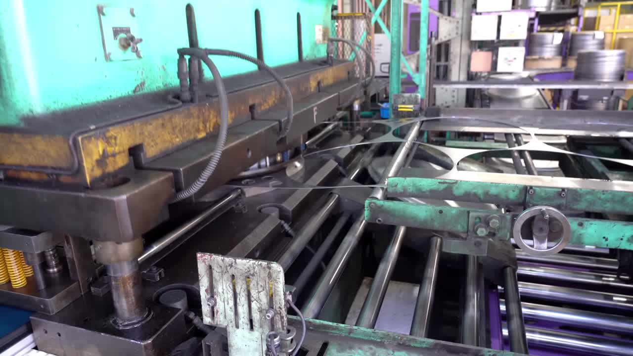 A machine stamps out drum can lids from large sheets of steel