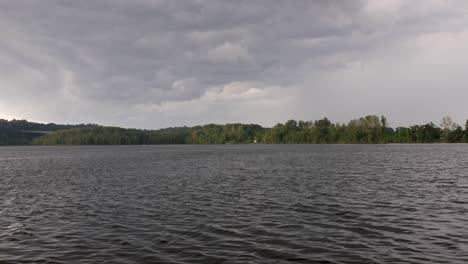 a tilt up from murky lake water rippling in the wind to reveal storm clouds