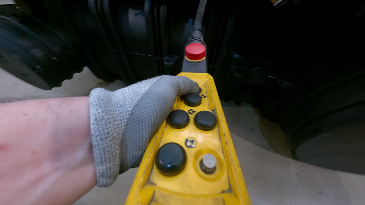 trabajador que opera un controlador de grúa industrial en una planta de fabricación