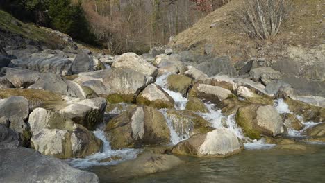 clear water flows over mossy rocks in a rugged mountain stream, surrounded by nature and trees