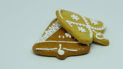 una mano pone un pan de jengibre de confitería con decoración blanca en la parte superior en forma de campana y corazón sobre un fondo blanco