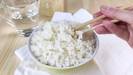 boiled white rice is stirred in round bowl with chopsticks and take serving