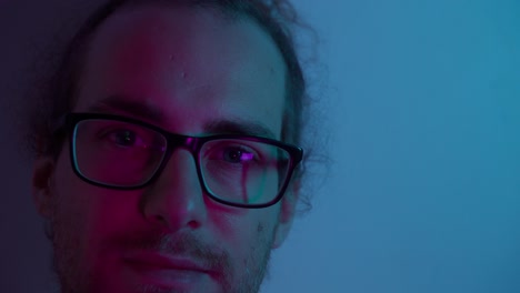 close-up portrait of a young man with glasses under neon lights