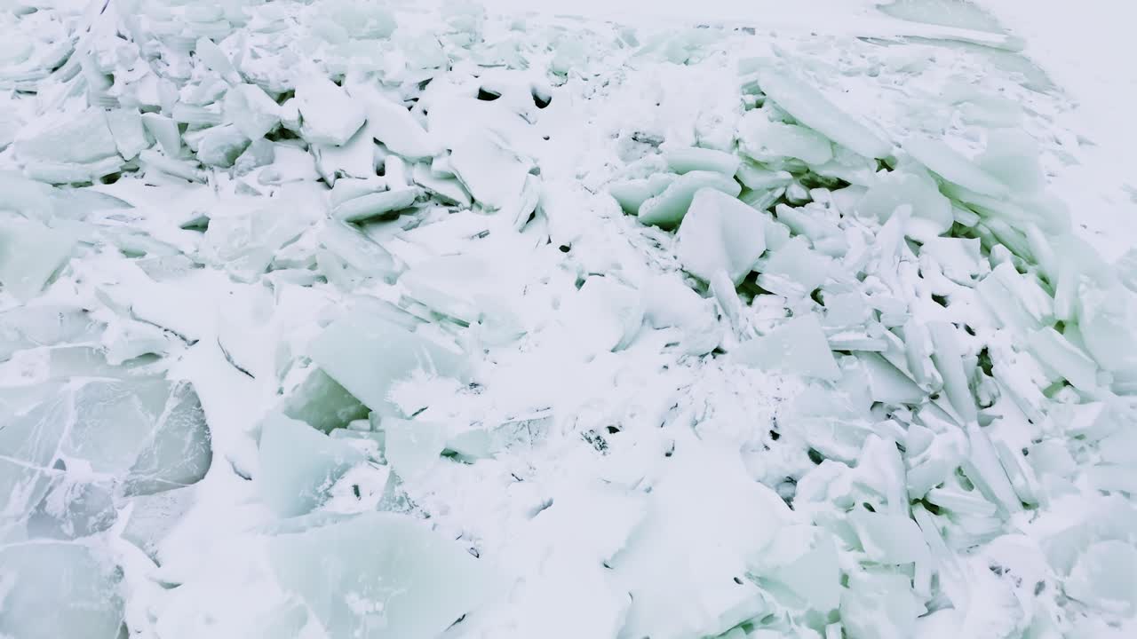 Primo piano aereo di banchisa frastagliata ammassata in creste su un mare ghiacciato, paesaggio invernale bianco con schegge turchesi e una drammatica texture naturale.