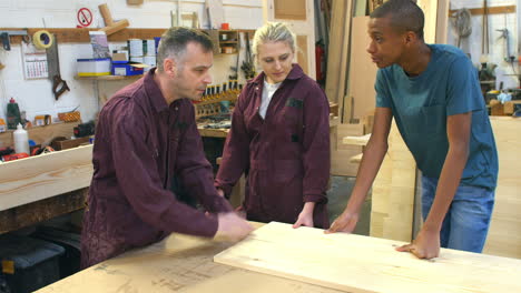 carpenter talking to apprentices in carpentry workshop