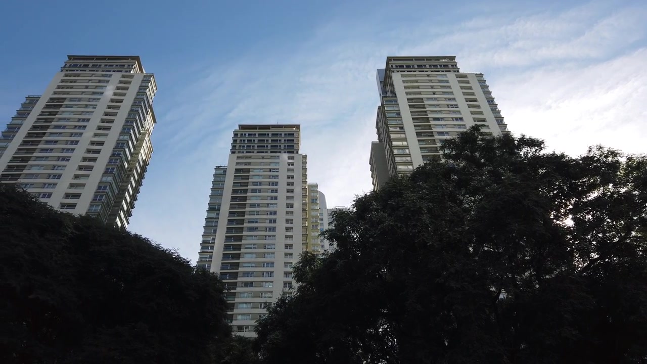 Panorámica en ángulo bajo de modernos rascacielos residenciales con árboles verdes en Puerto Madero, Buenos Aires, Argentina.