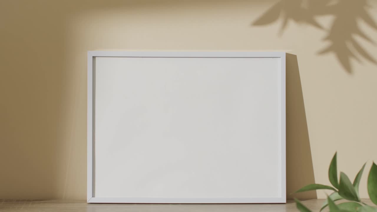 marco negro con espacio de copia en fondo blanco y sombra de hoja contra la pared amarilla