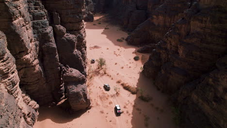 drone shot of vehicles driving through sahara desert in tassili n'ajjer national park, algeria