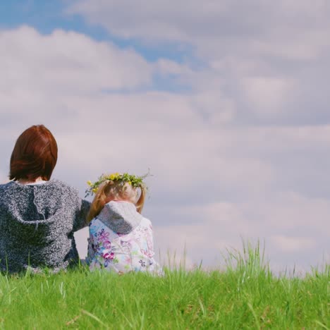 rear view of a middle-aged woman with her daughter making a wreath of wild flowers together