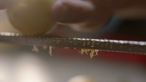 detail of person zesting lemon peel with kitchen utensil