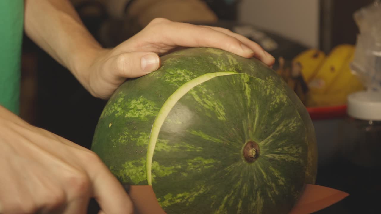 mano sosteniendo un cuchillo afilado cortando los extremos de una sandía - toma de primer plano