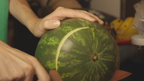 Hand,-Die-Ein-Scharfes-Messer-Hält,-Das-Die-Enden-Einer-Wassermelone-Abschneidet---Nahaufnahme