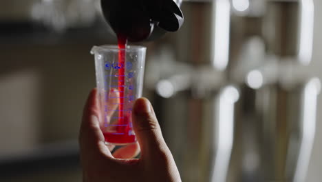 pouring red liquid into measuring cup