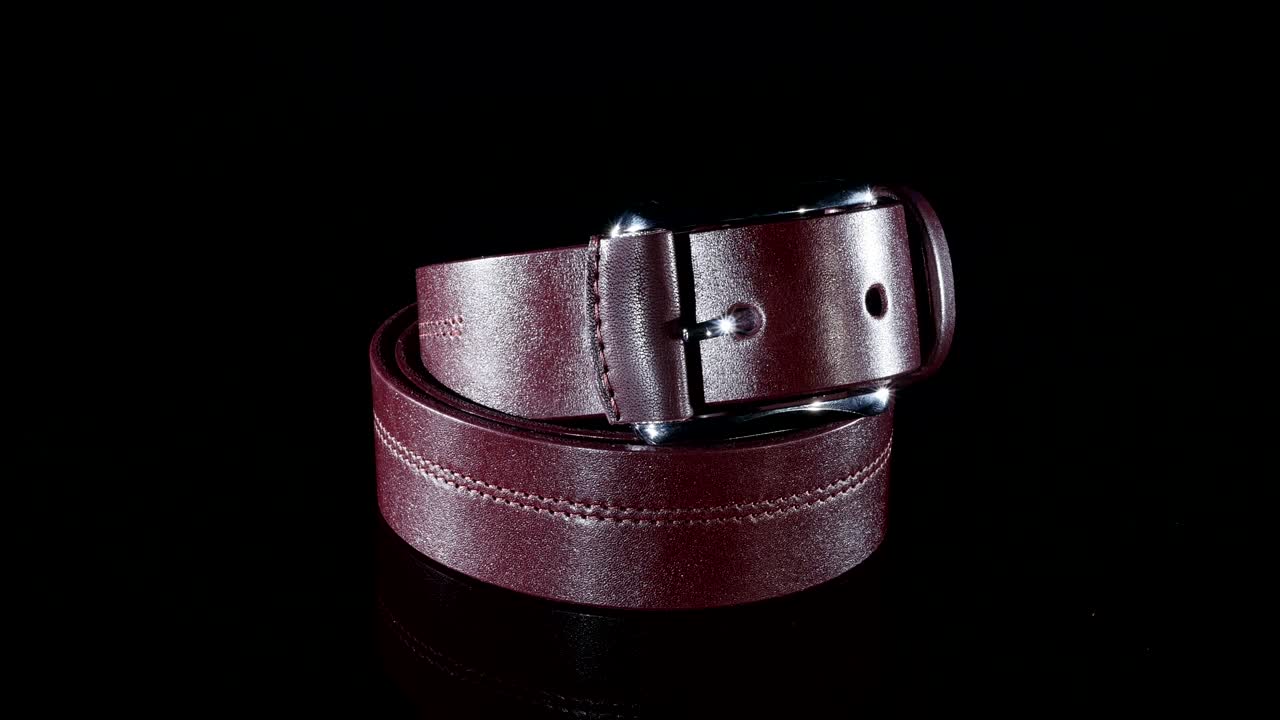 갈색 남성의 벨트는 검은색 배경에 회전합니다.