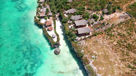 Pequeña-Bahía-Paradisíaca-Con-Arena-Blanca,-Agua-Azul-Rodeada-De-Plantas-Verdes-Y-Un-Restaurante