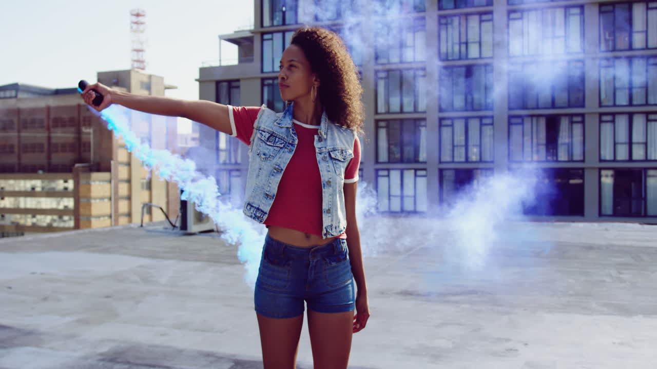 mujer joven de moda en el techo urbano usando una granada de humo