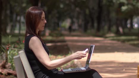 young woman opens her computer, portable working in city park