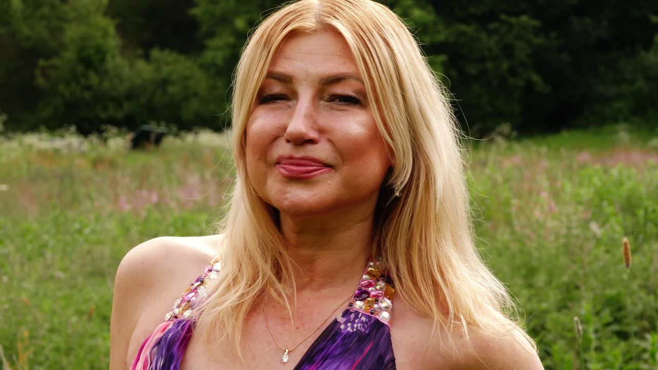 привлекательная счастливая женщина смотрит в камеру на фоне природы средний портрет 4k в замедленном движении