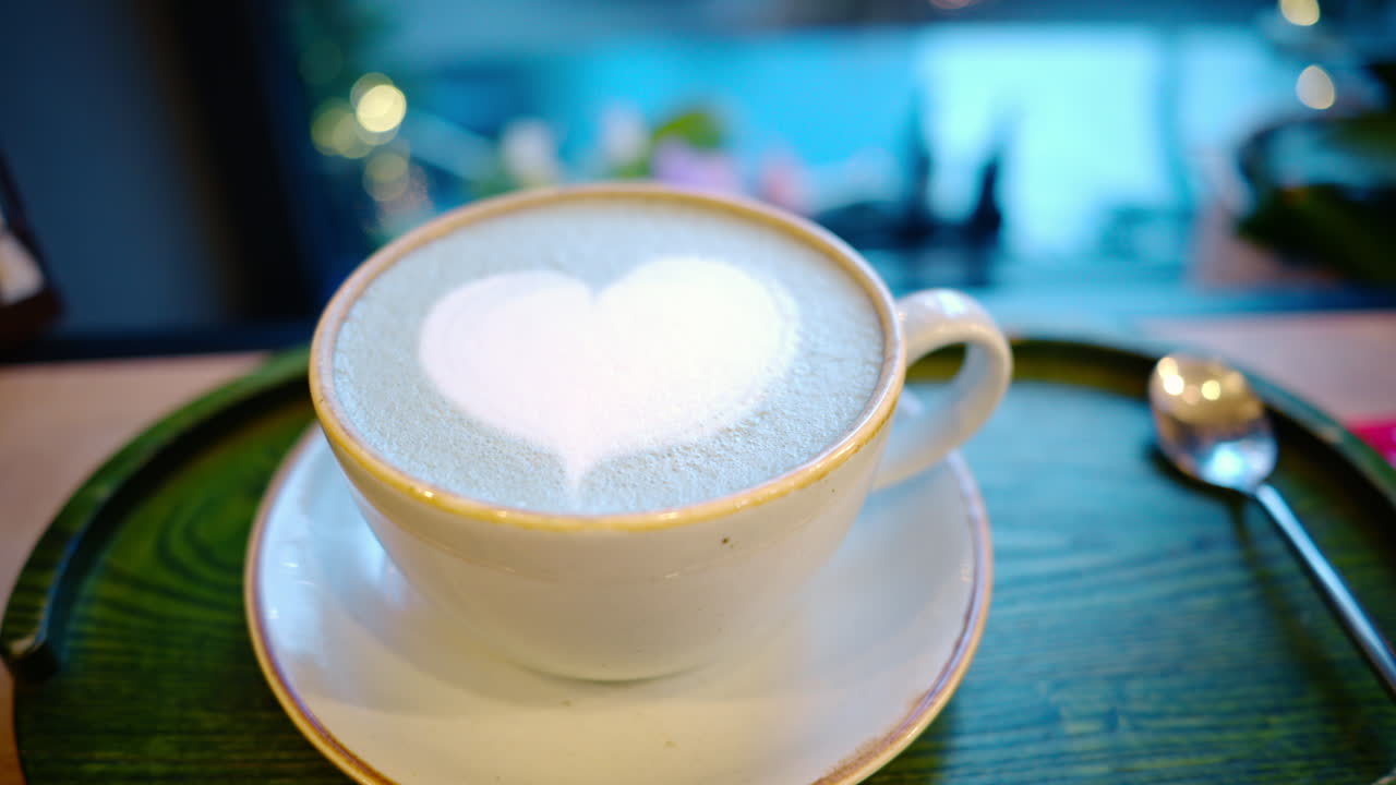 Cup of coffee with foam latte art in heart shape. Christmas tree on background