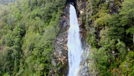 órbita aérea de la cascada del río blanco rodeada por el bosque del parque nacional hornopirén, chile