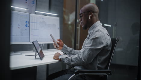 financial analyst suffering from financial crisis, yelling in phone, analyzing exchange market charts in office. african american businessman furious about stock market collapse. vertical shot.