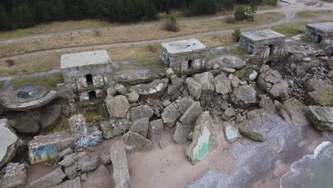 aerial view of abandoned seaside fortification building at karosta northern forts on the beach of baltic sea in liepaja in overcast spring day, pine wood, wide revealing drone shot moving forward