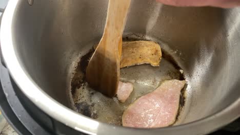 top down view of cooking of chicken breast in pot in slow cooker and flipping them - turning sizzling chicken breasts in pot and oil