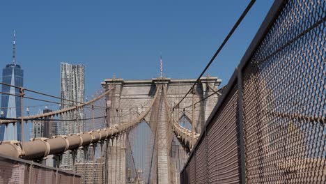 slow motion pan of landscape wires arches of brooklyn bridge overpass new york city cbd with skyscrapers towers buildings usa america urban tourism architecture engineering