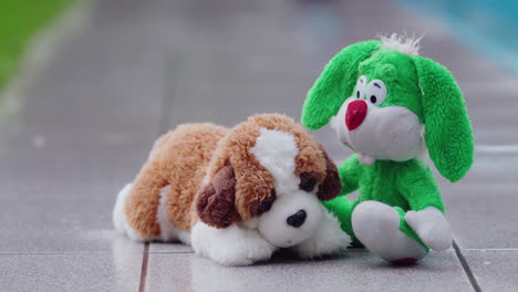 two soft toys - a hare and a puppy get wet in the rain in the backyard of the house