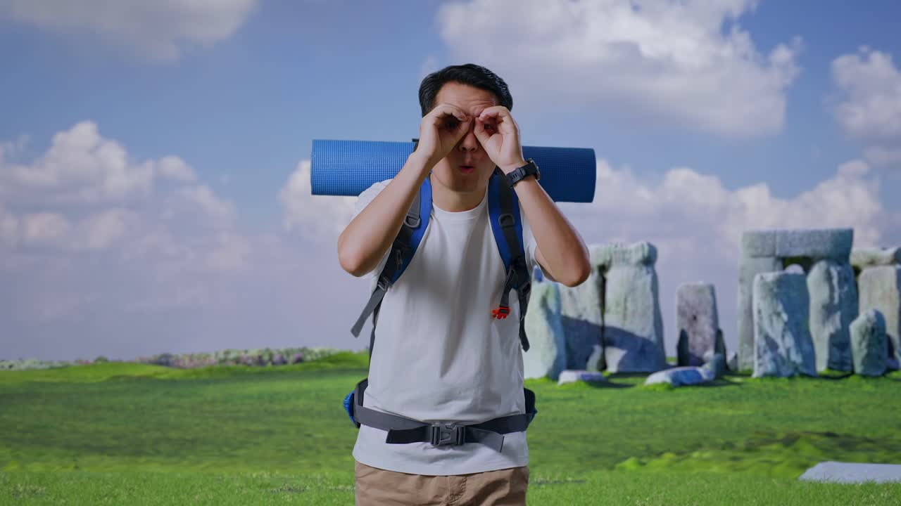 Asian Male Hiker With Mountaineering Backpack Making Binoculars Gesture Looking At Something Then Saying Wow While Traveling In Stonehenge