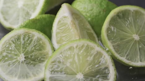 Video-of-water-drops-falling-onto-sliced-limes-with-copy-space-on-white-background