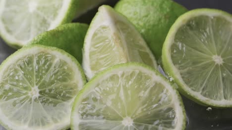 video de gotas de agua cayendo sobre limas en rodajas con espacio de copia en fondo blanco