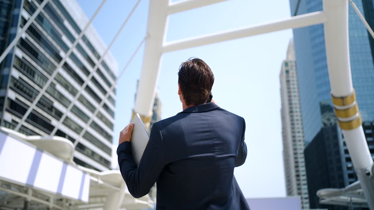 hombre de negocios caucásico con una tableta usando un teléfono inteligente caminando por la ciudad
