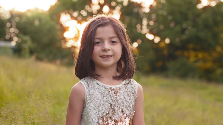 Niña sonriente en un campo al atardecer