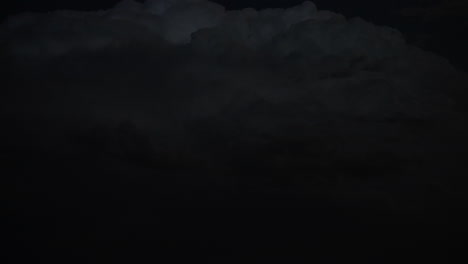 lightning flashes within dark storm clouds at night