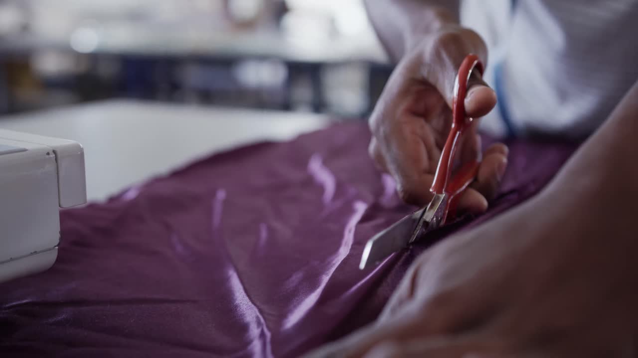 hombre de raza mixta cortando telas en la oficina de moda
