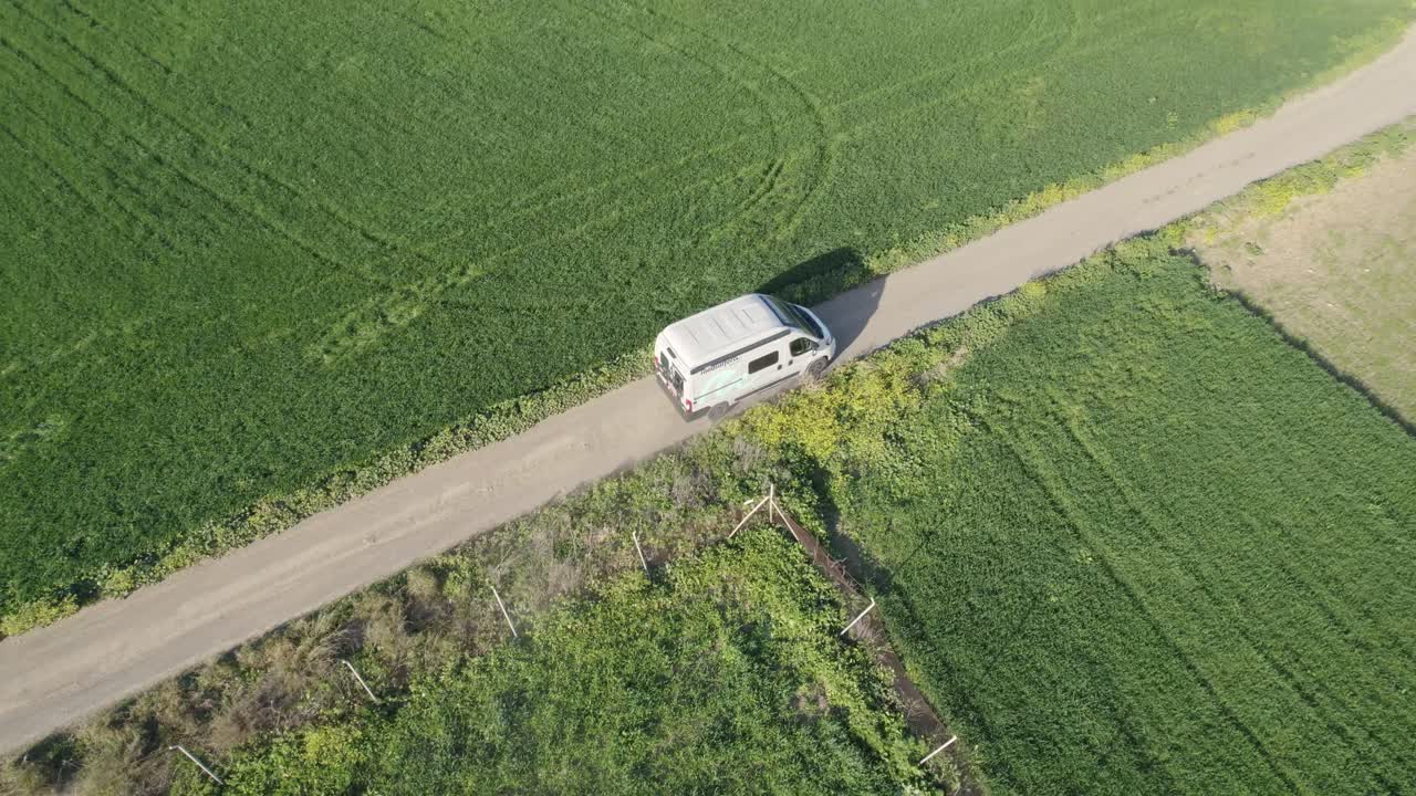 Video aereo che segue un'auto su una strada in un campo erboso durante una giornata a Huelva, Spagna