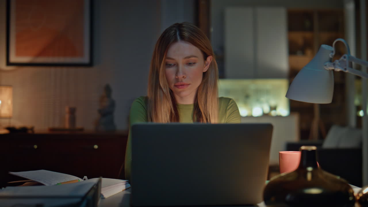 Online student studying late evening looking laptop. Woman freelancer working