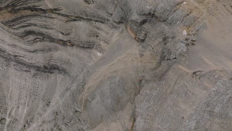 spectacular aerial birds eye flight between steep mountain rock wall edge in mountain peak in italy