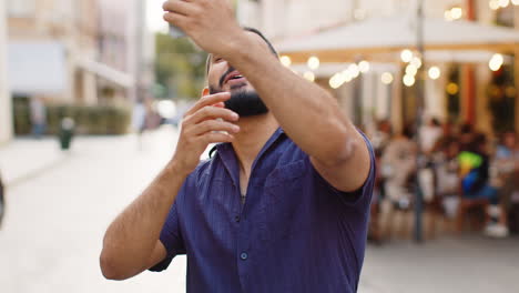 young man blogger taking selfie on smartphone video call online with subscribers in city street