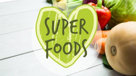 animation of superfoods text in green on green heart, over fresh vegetables on white boards