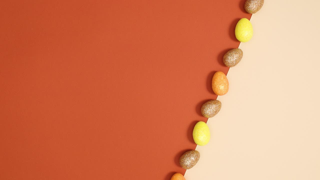 huevos de pascua brillantes se mueven en línea en desnudo y ladrillo de fondo de color rojo. detener el movimiento mínimo de colocación plana